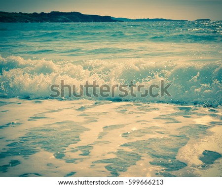 Waves breaking on a sandy beach on the shore of the mediterranean coast. Vintage stylized photo.