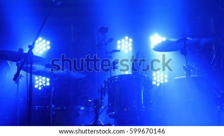 The scene with the drum kit and beautiful searchlights in blue colors