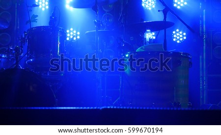 The scene with the drum kit and beautiful searchlights in blue colors