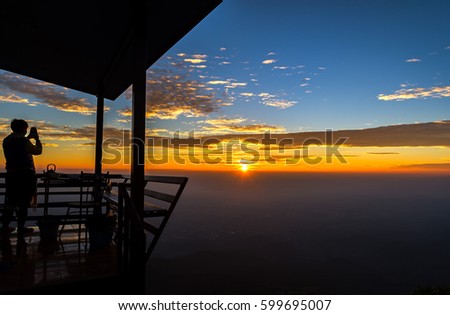 Silhouette of a man standing take a photo on the mountain in  on sunrise