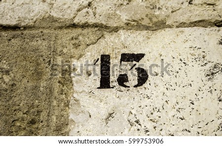 Number thirteen in stone wall, sign and symbol