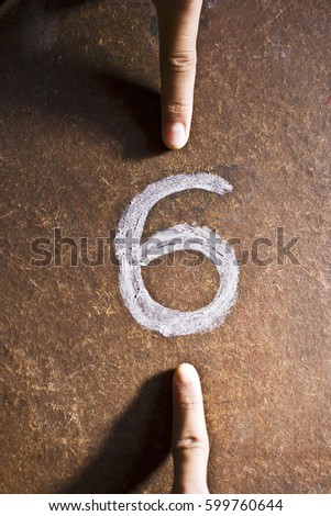 two human fingers arguing whether a number on the floor is a 6 or a 9. Concept of ideological perspective. Royalty-Free Stock Photo #599760644