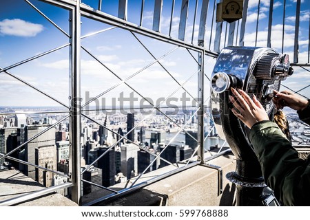 Close up of a girl that looks manhattan by telescope, from the Empire State Building Royalty-Free Stock Photo #599768888