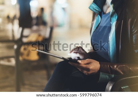 Girl holding in hands on blank screen tablet on background illumination glow light in night atmospheric city, hands using template mobile computer on lights glitter street; mock up gadget