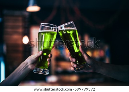 Two friends toasting with glasses of green beer at the pub with free space for your text. Beautiful background of the Oktoberfest and St. Patrick's day. fine grain. Soft focus. Shallow DOF.
