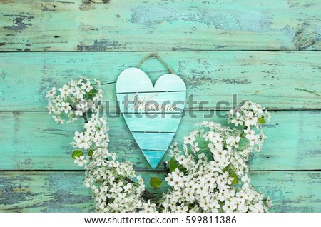 Welcome pallet heart sign hanging on antique rustic teal blue wood background by spring tree blossoms; springtime, Valentines Day or Mothers Day background with painted copy space