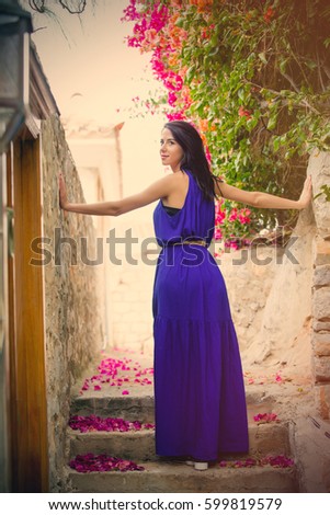 photo of beautiful young woman standing on the stairs near blooming tree in Greece