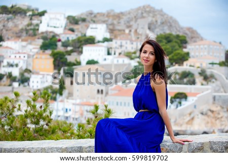 photo of beautiful young woman sitting on the stairs on the town background in Greece