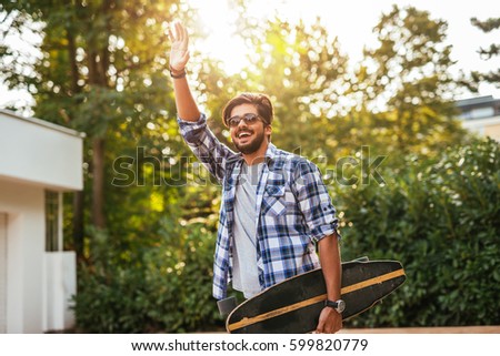 Shot of a male with sunglasses who carries a skateboard in the city.