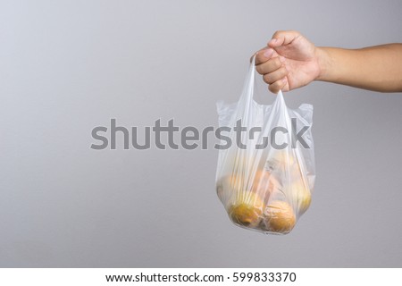 Hand holding plastic bag full of oranges on white background Royalty-Free Stock Photo #599833370