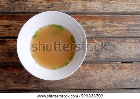 A bowl of clear soup with vegetable on wood table served with noodle or rice as a side dish or appetizer, asian unique style of noodle cooking with delicious good smell soup 