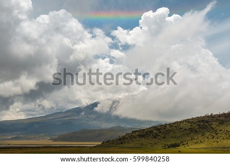 Landscape along the trekking inside the Cotopaxi national park with a horizontal rainbow, a wild horse and the volcano in the clouds, Ecuador.