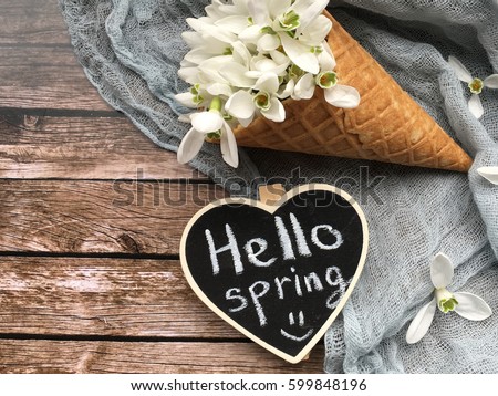 hello spring chalkboard with snowdrops in waffle cup. hello spring on chalkboard. shabby spring. girl holds a heart chalkboard for spring Royalty-Free Stock Photo #599848196