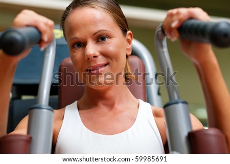 Woman doing fitness training on a butterfly machine with weights in a gym