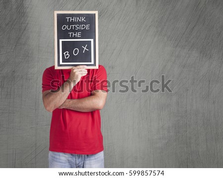 Man holding a board with think outside the box message