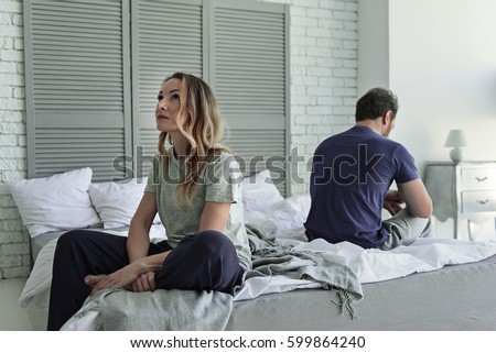 Sad couple sitting on bed Royalty-Free Stock Photo #599864240