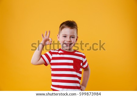 Portrait of a cute little boy kid showing okay gesture isolated over orange background