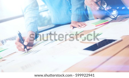 Closeup view of teamwork concept.Young business team working with new startup project.Smartphone on wooden table,documents and marketing reports.Blurred background,visual effect,flare.Horizontal.