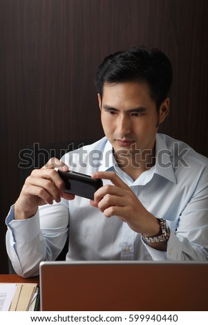 man sitting at desk looking phone