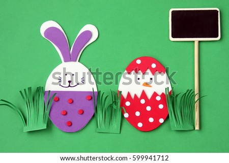 easter hand made decorations: festive plastic foam bunny and egg with blackboard isolated on green background with copy space