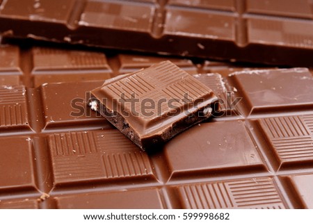 Chocolate bars as background. Milk and dark shiny chocolate texture. Stack chocolates pattern. Stunning beautiful cacao brown dessert sweets. 
 