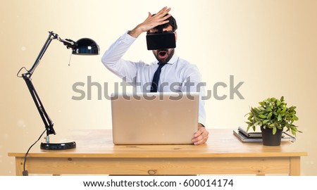 Businessman in his office using VR glasses on ocher background
