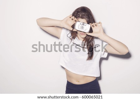 Hipster girl using a vintage 35mm camera, ready to shot!. In studio, over a white background.