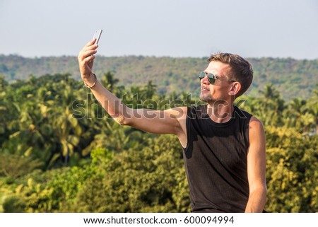 Young man is making a selfie photo from a mobile phone, Goa, India.