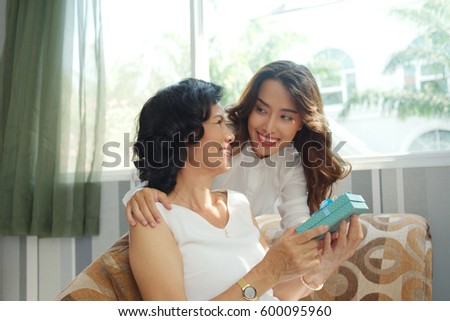 Pretty young woman giving present to her mother
