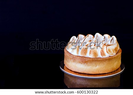 Tartlet with meringue and lemon on a black background isolated close-up