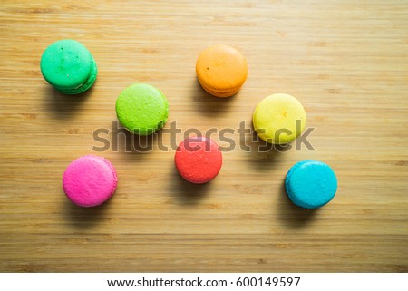 Cake macaron or macaroon on turquoise background from above, colorful almond cookies on the wood texture table giving some space for editing and retouching