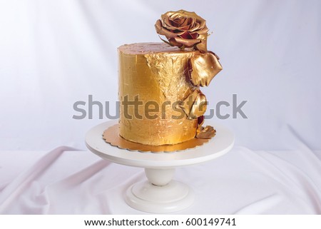 wedding cake decorated gold with flowers rose on a background of wavy fabric. trends for wedding desserts, food design
