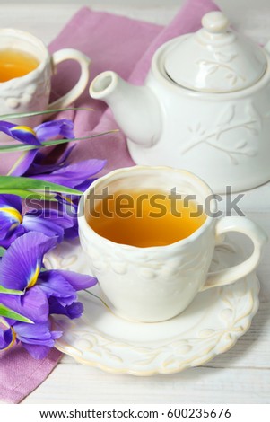 Beautiful fragrant daffodils, cup with tea and teapot on a wooden background