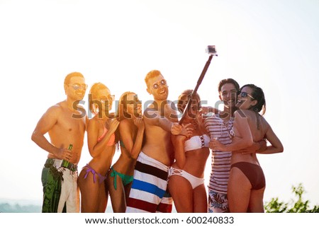Group of young cheerful people taking selfies in swimwear