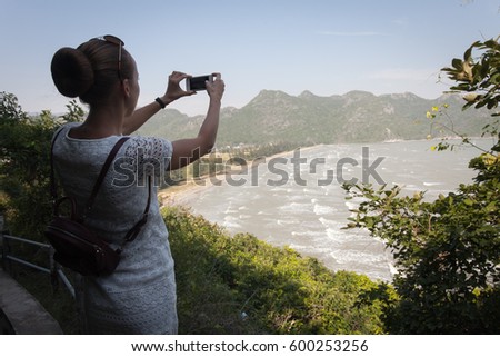 High point of shooting on the bay surrounded by mountains. The girl takes a picture on the smartphone. Selfy.