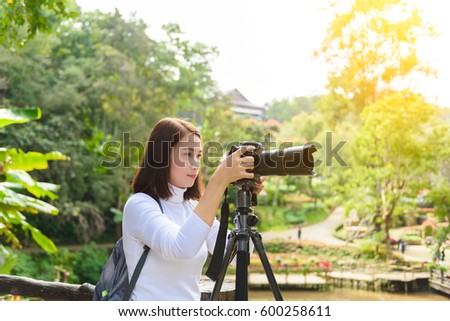 Female photographer with Tripod taking pictures of flowers in flowers garden