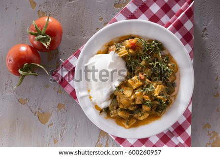 Steamed vegetables with rustic roasted potatoes, eggplant, zucchini, peppers, fresh cherry tomatoes, rosemary, basil, thyme in ceramic bowl on dark grey rustic concrete background, angle view