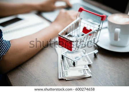 Red shopping cart and laptop on wooden table,shopping online concept.