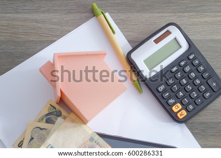 Calculator, pen,mini house, money and paper. Concept of home buying, tax,rental,investment,mortgage,agreement and other issues.