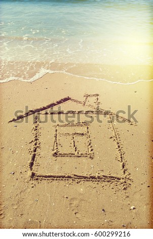 drawing of house on sand and a sea wave .Toned photo on retro style