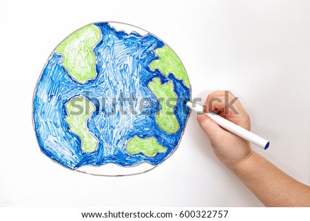Child's hand drawing planet Earth with a marker. Close up.