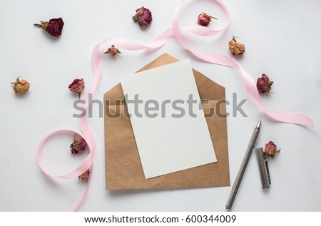 Workspace. Wedding invitation cards, craft envelopes, pink and red roses and green leaves on white background. Overhead view. Flat lay, top view wedding invitation card Templates