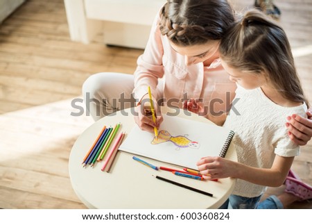 high angle view of mother and daughter drawing picture together