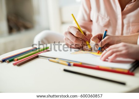 partial view of mother and daughter drawing picture together