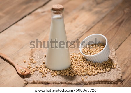 A bottle of soy milk or soya milk and soy beans on wooden table. 