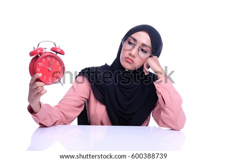 Portrait of unhappy Muslim girl hold a alarm clock with white background. Time conceptual for work