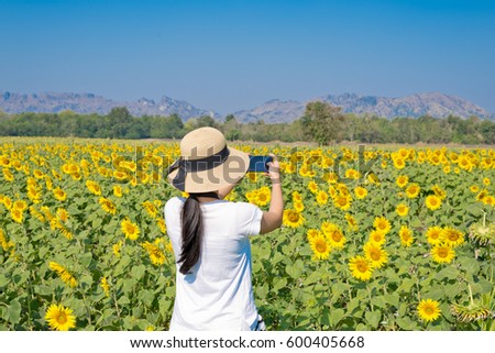 Selective focus on the girl take photo on sunflowers field with blue sky background