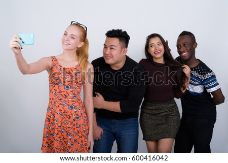 Happy diverse group of multi ethnic friends smiling while taking selfie picture with mobile phone together