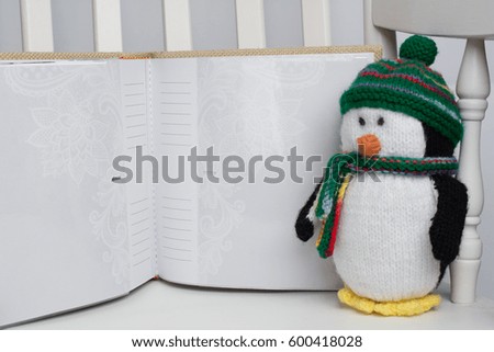 Stuffed penguin toy on white rocking chair with photo album