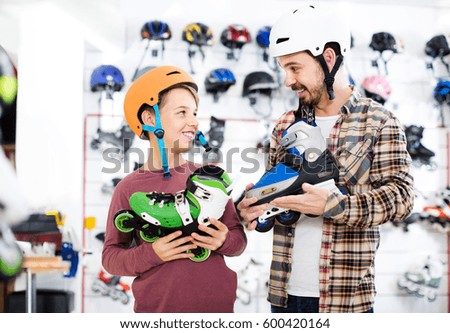 Young father and son deciding on new roller-skates in sports store